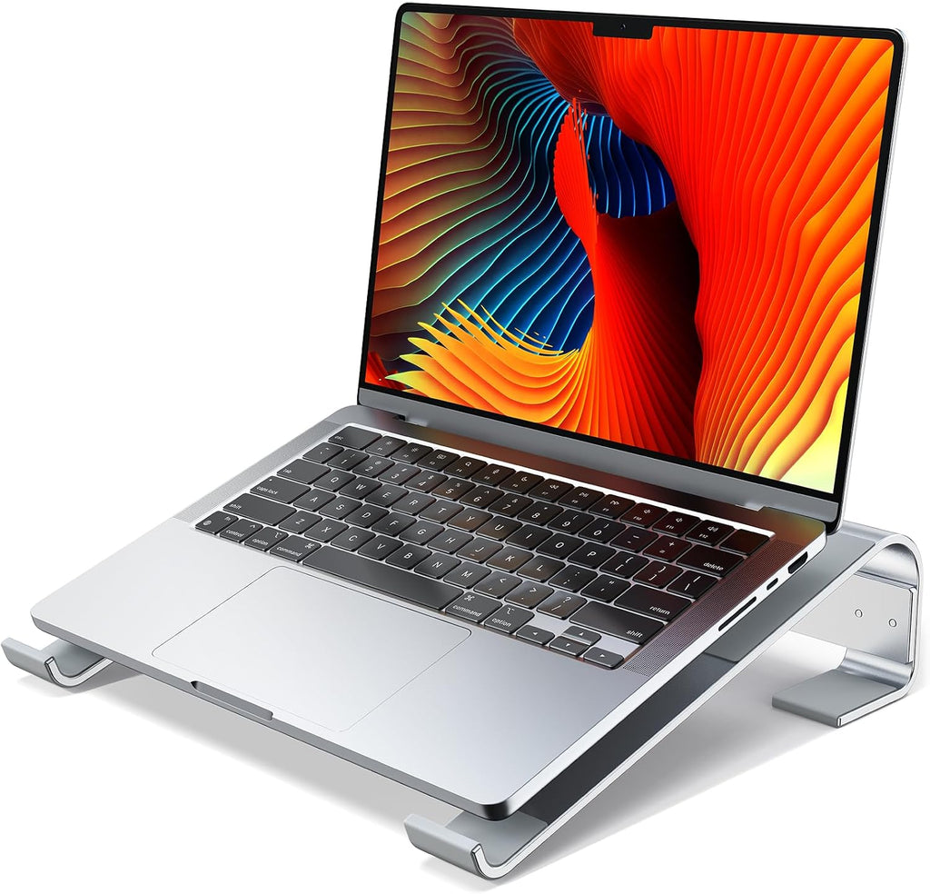 Soporte elevador ergonómico de aluminio plateado con MacBook, vista 3/4 frontal sobre fondo blanco