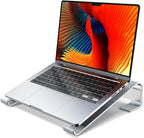 Soporte elevador ergonómico de aluminio plateado con MacBook, vista 3/4 frontal sobre fondo blanco